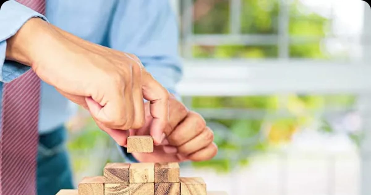 Hands stacking wooden blocks, representing the building blocks of software cost