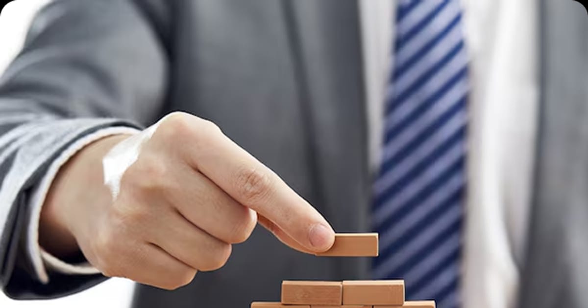 Hand placing a block on a stack of bricks, representing building custom software step by step