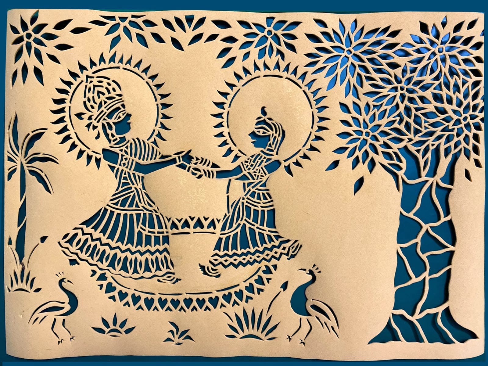 Paper-cut Sanjhi of Radha and Krishna dancing beneath a tree, peacocks at their feet
